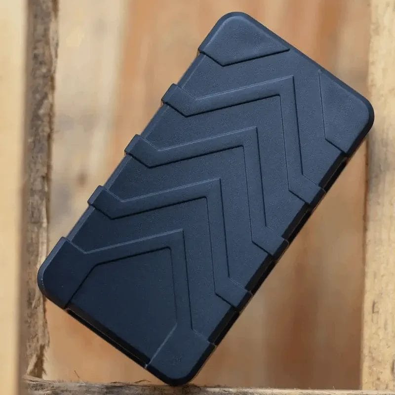 A rectangular electronic device in matte black sitting on a wooden surface.